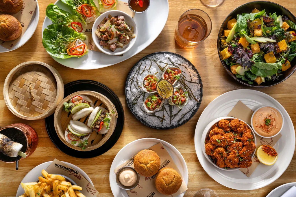 A feast of various dishes spread out on a wooden table.