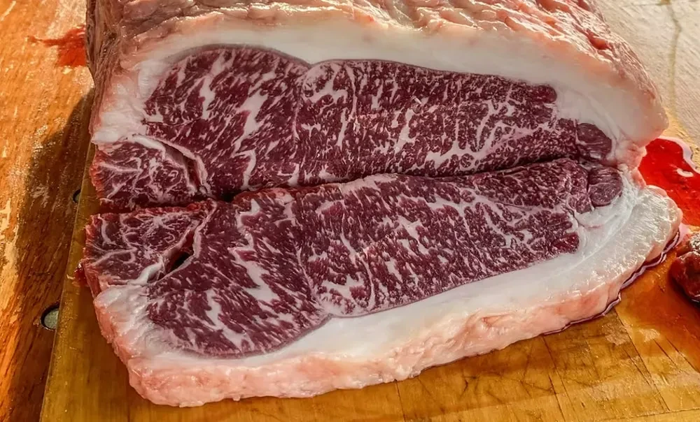 A close-up shot of a raw, marbled Wagyu steak on a cutting board.