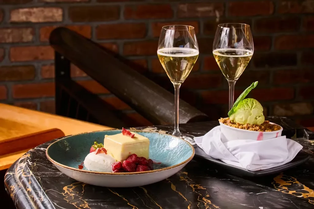 Two desserts and two glasses of champagne on a marble table.