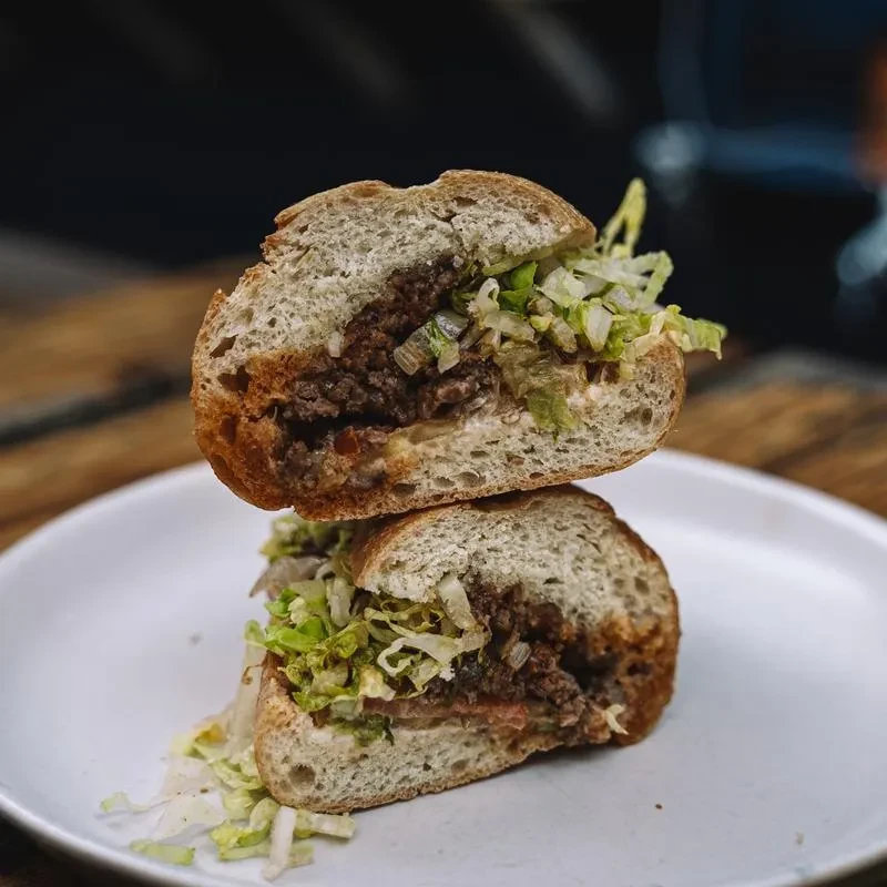 Two halves of a meat and lettuce sandwich on a white plate.