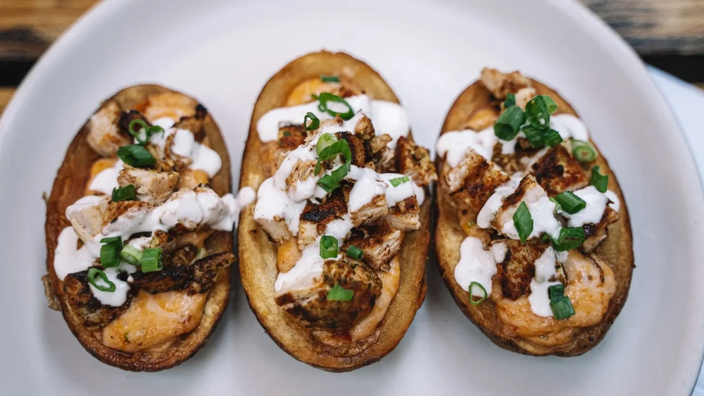 Three chicken and cheese potato skins with sour cream and chives.