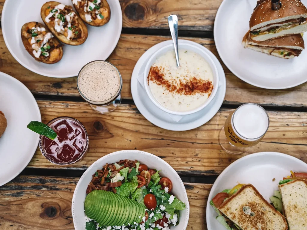 An overhead view of various dishes and drinks on a wooden table.
