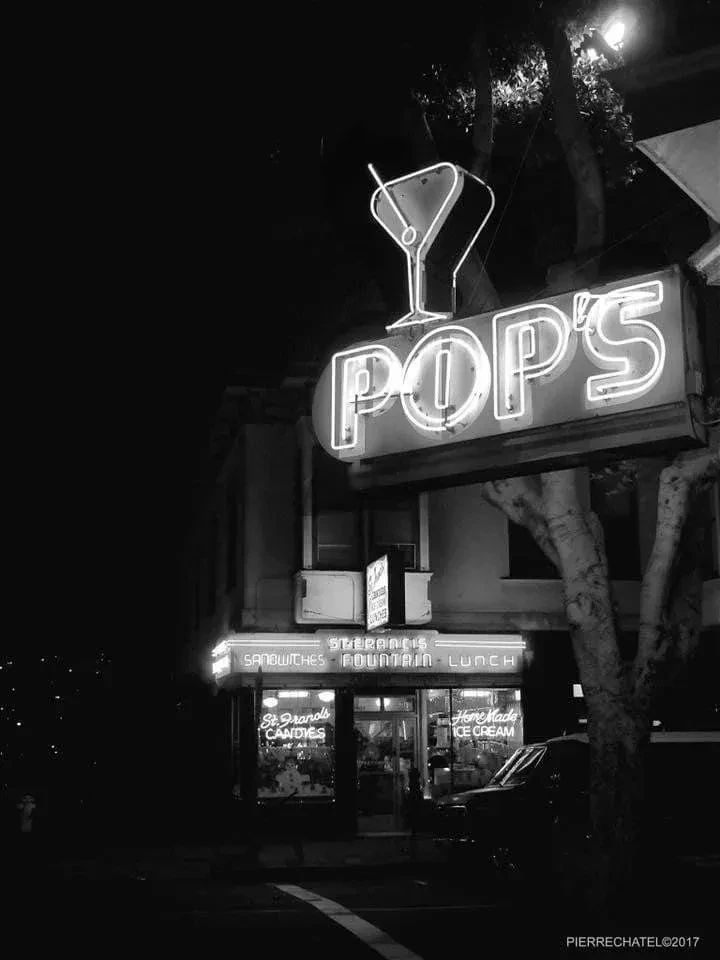 Black and white photo of Pop's neon sign above a storefront.