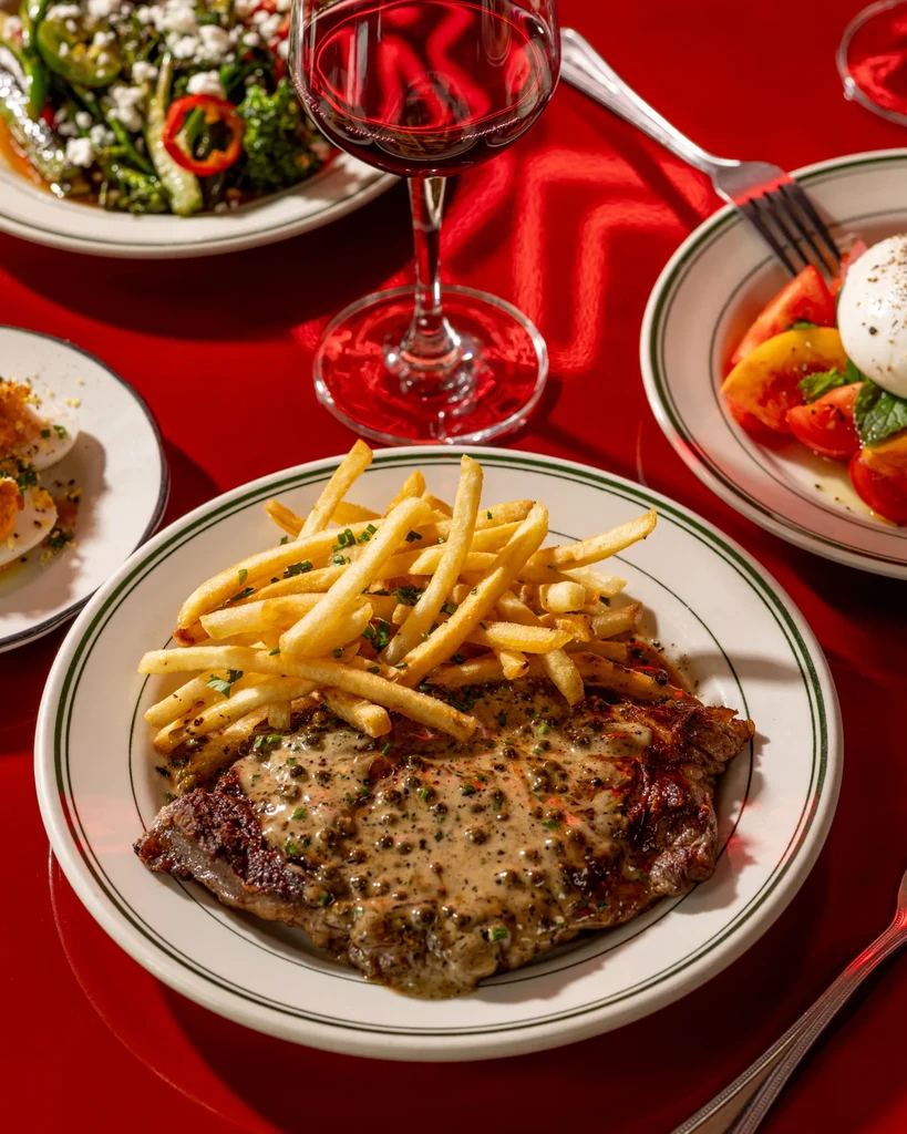 Steak frites and other dishes on a red table.