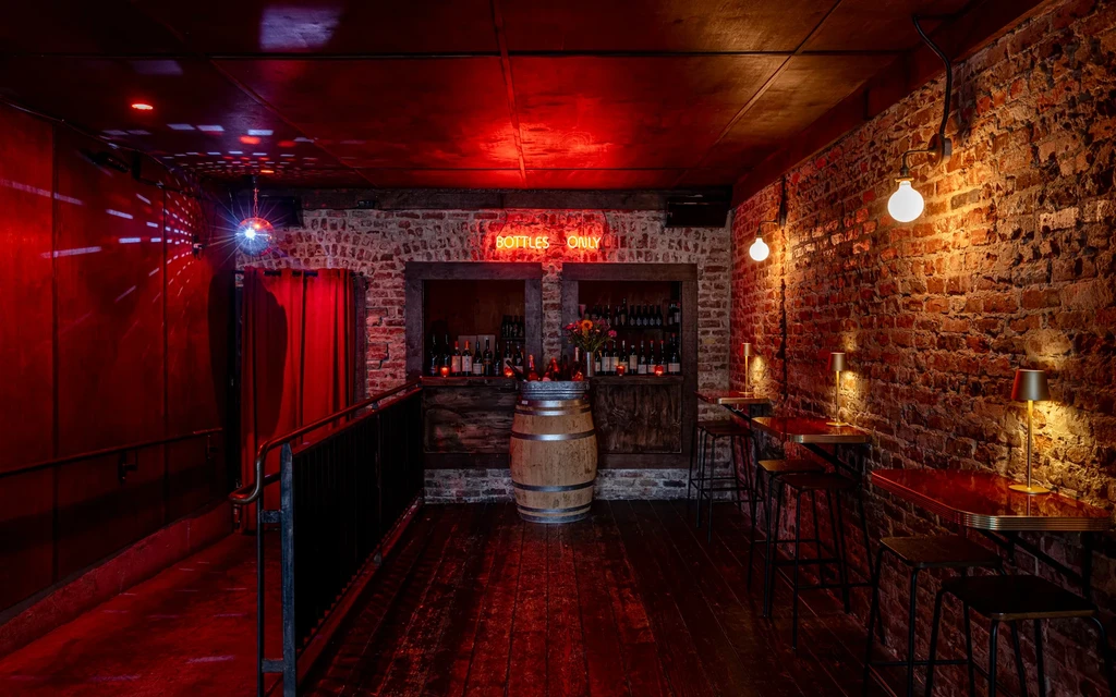 A dimly lit, red-hued bar with brick walls and a disco ball.
