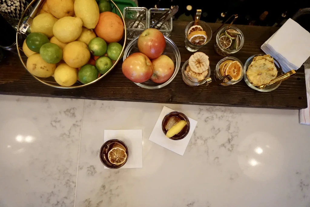Overhead view of a bar with fresh and dried fruits and two drinks.