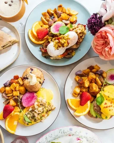 Overhead view of several plates of brunch food on a light table.