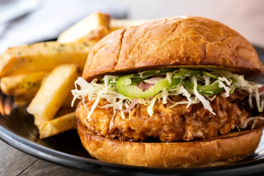 A close-up of a chicken burger with fries on a plate.