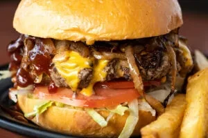 A cheeseburger with caramelized onions, barbecue sauce, and fries.