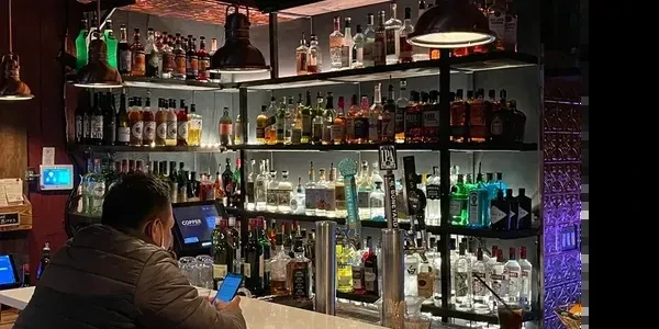 A person sits at a bar counter looking at their phone.