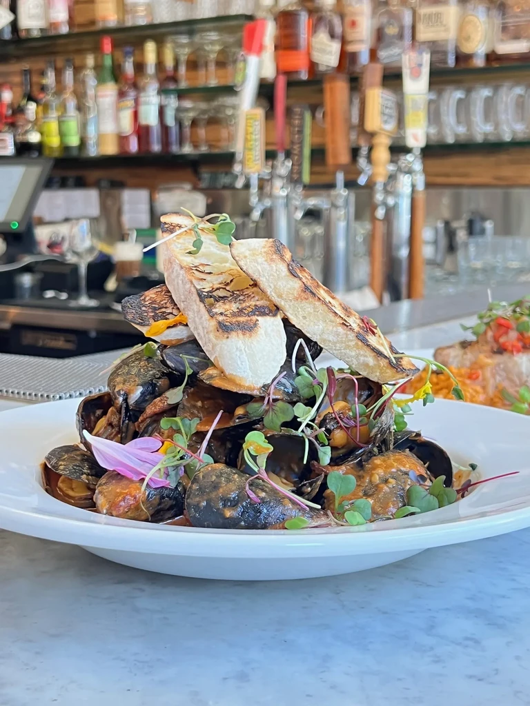 A plate of mussels topped with bread in a restaurant setting.
