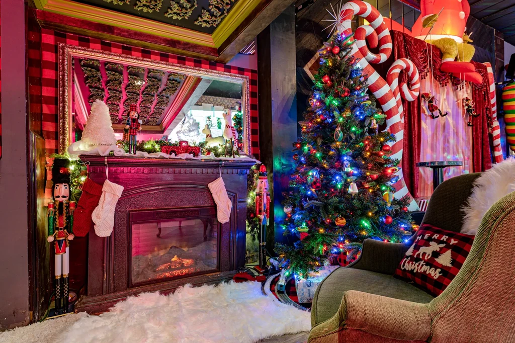 A cozy room decorated for Christmas with a fireplace and Christmas tree.