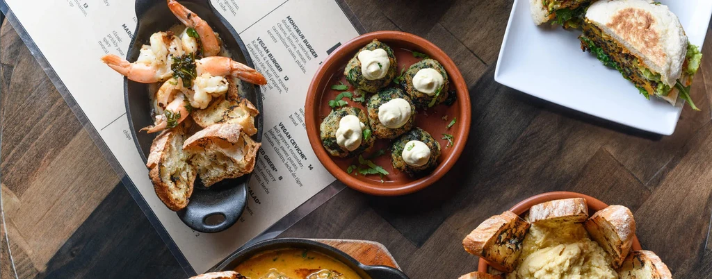 Overhead shot of various dishes from a restaurant menu on a wood table.