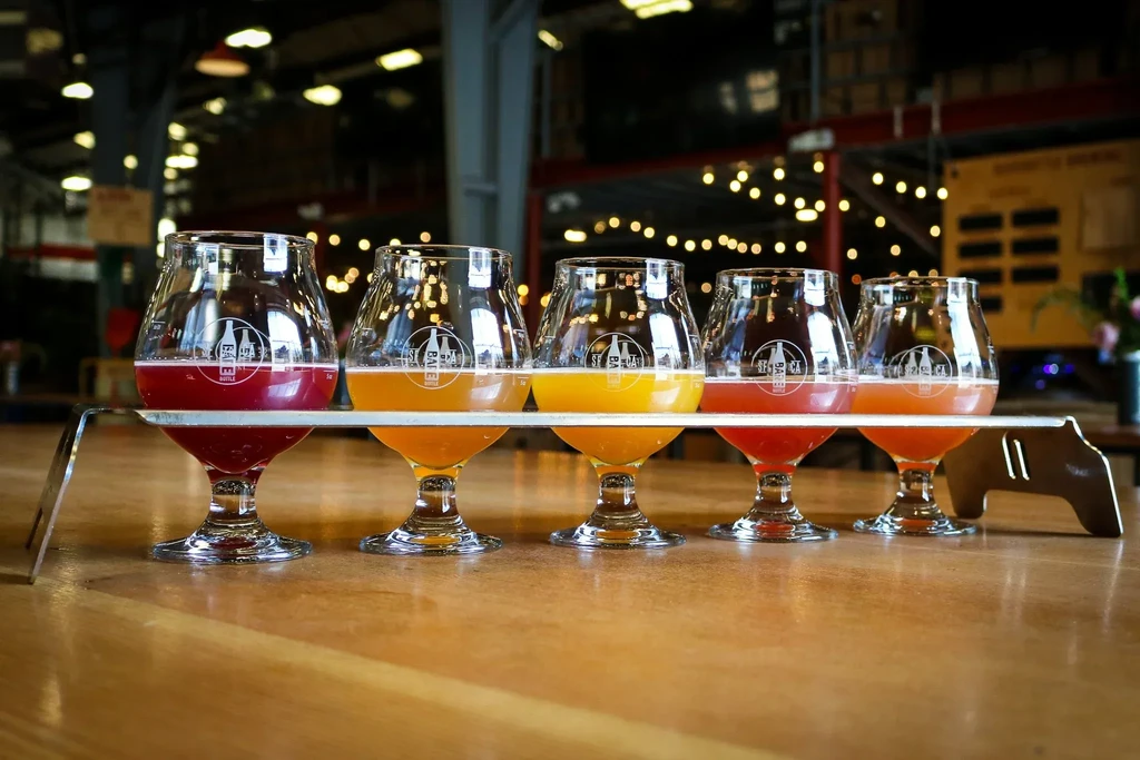 Five glasses with different colored drinks on a serving tray.