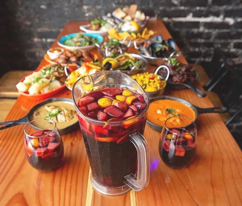A table filled with a large pitcher of sangria and various tapas dishes.