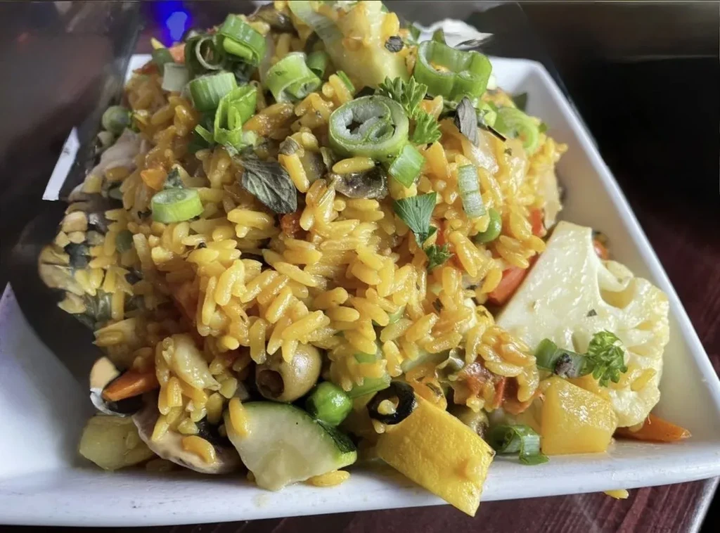 A close-up shot of yellow rice and vegetables on a white plate.