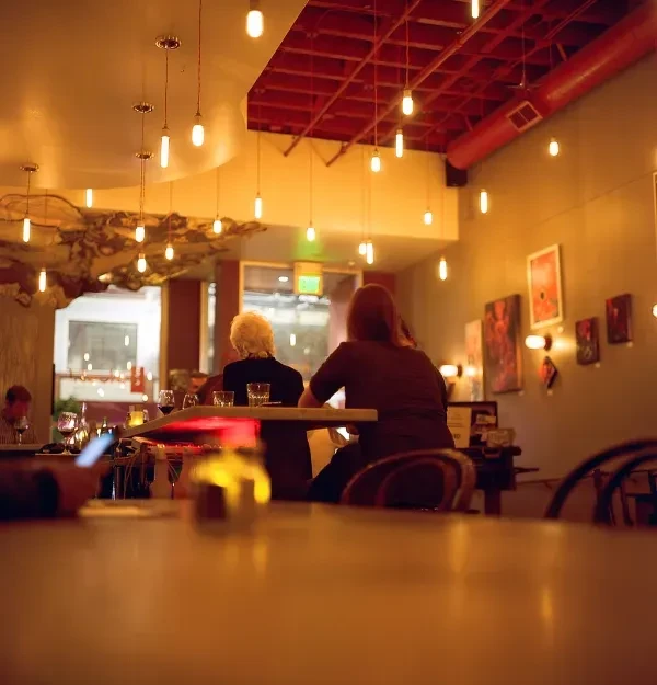 Two women seated at a bar in a warmly lit restaurant.