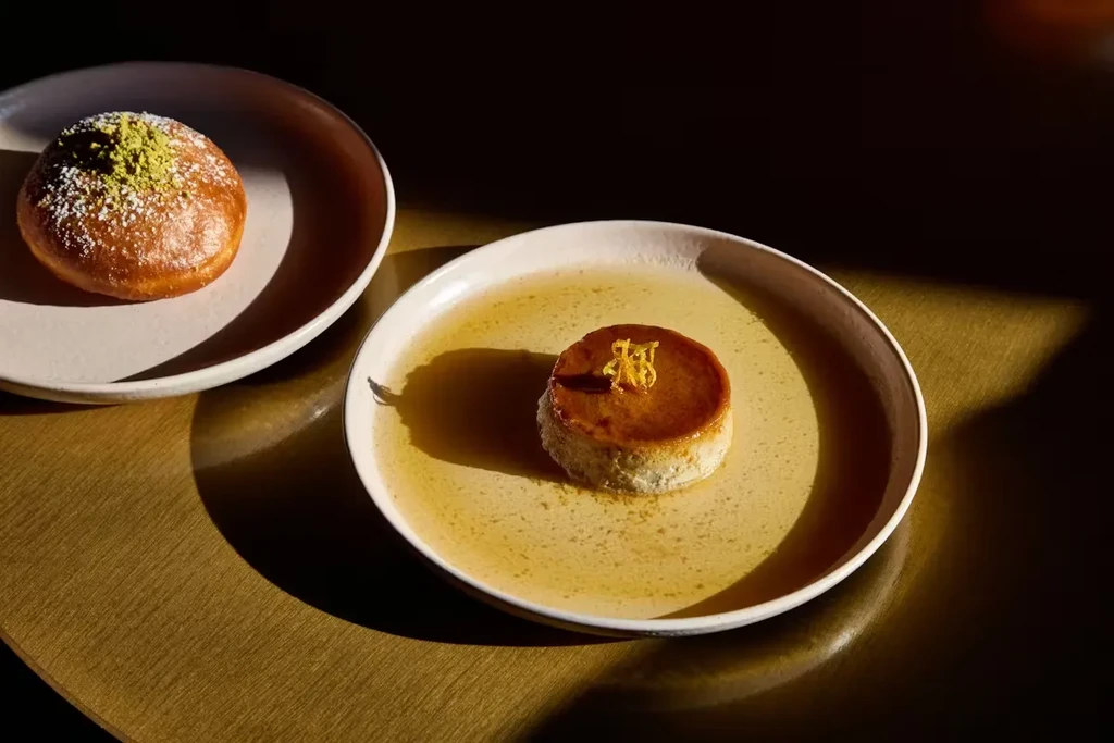 Flan and donut on plates, with sunlight creating deep shadows.