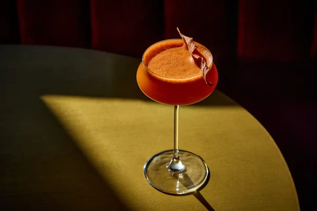 A red cocktail with a chocolate garnish on a table.