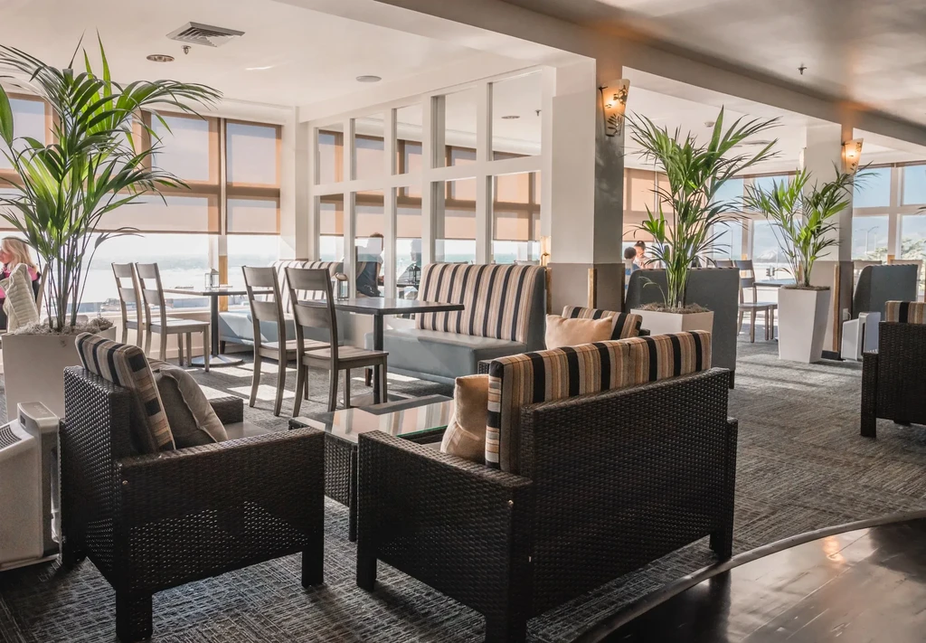 A modern lounge with dark wicker furniture, striped cushions, and potted plants.
