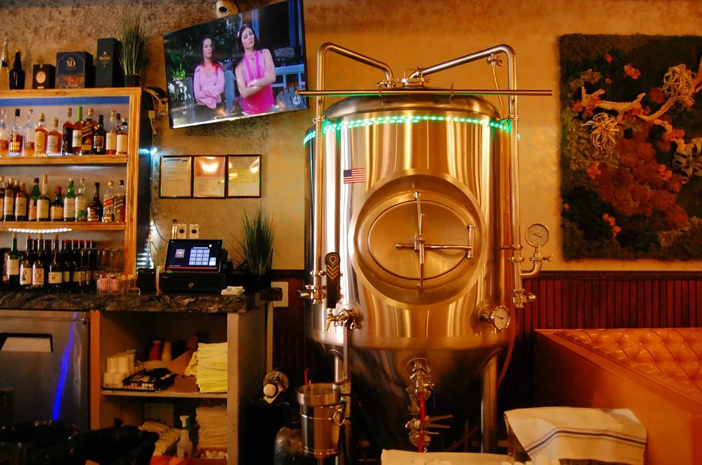 A brewery or bar interior with a large stainless steel brewing tank.