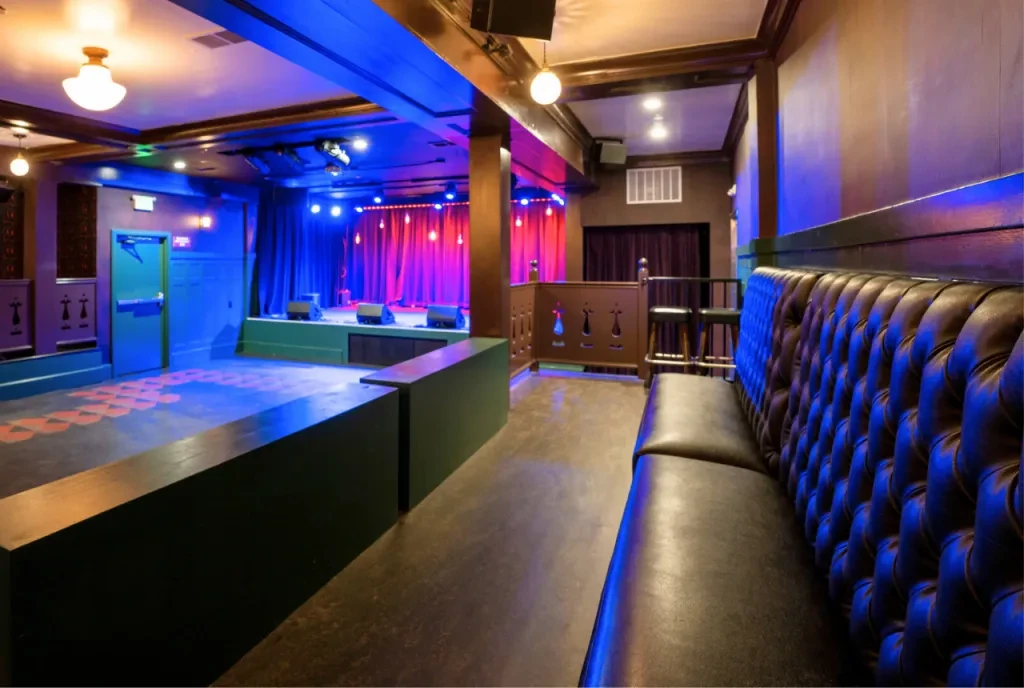 An empty music venue with a stage and a long leather bench.