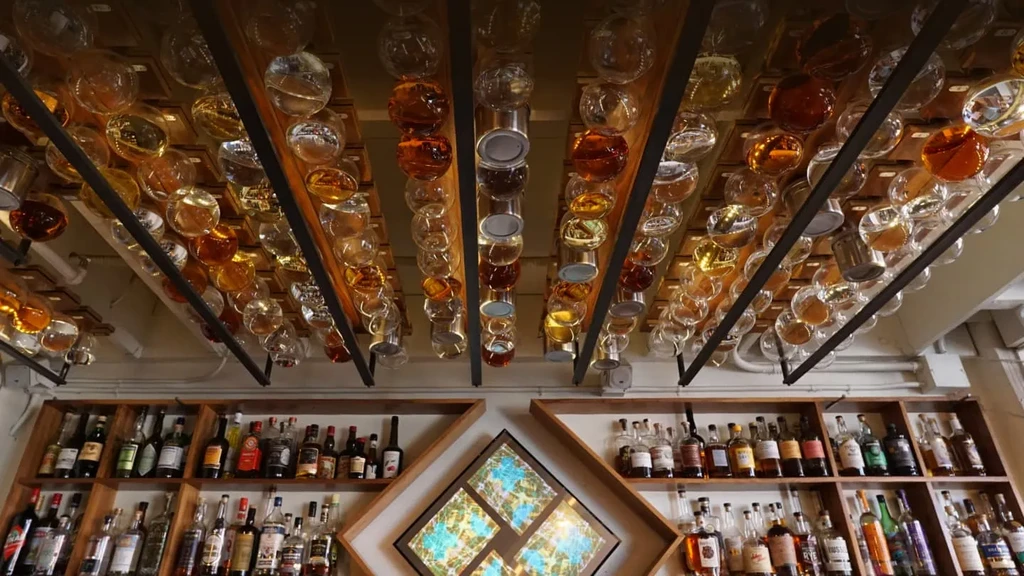 Numerous bottles hang inverted from the ceiling above a bar.