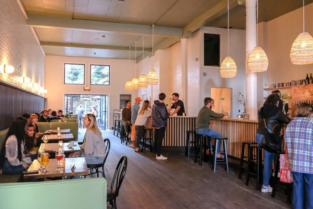 People dining in a casual restaurant with a long bar and booth seating.