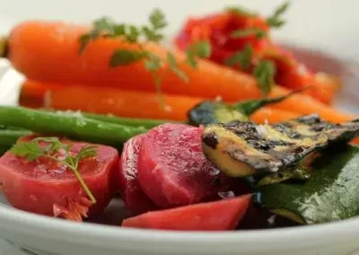 A white bowl of cooked carrots, green beans, beets, and grilled zucchini.