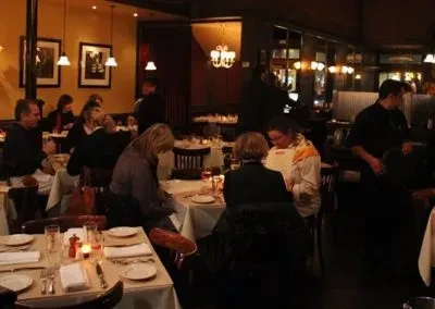 People dining in a warm, dimly lit restaurant with waiters working.