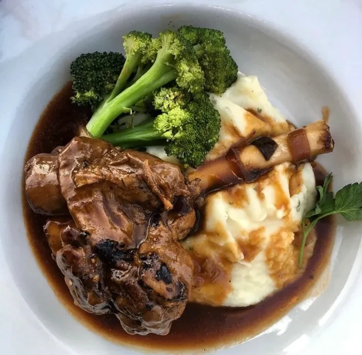 Braised lamb shank with mashed potatoes, broccoli, and gravy.
