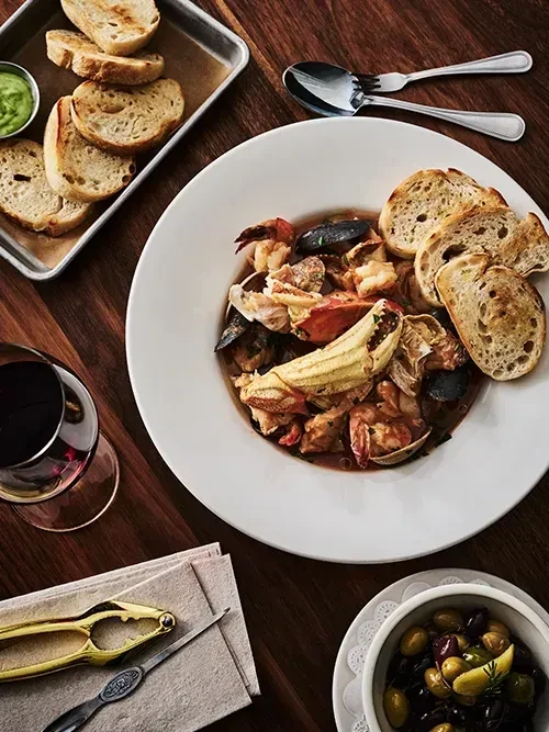 A bowl of cioppino with crab, mussels, shrimp, and toast.