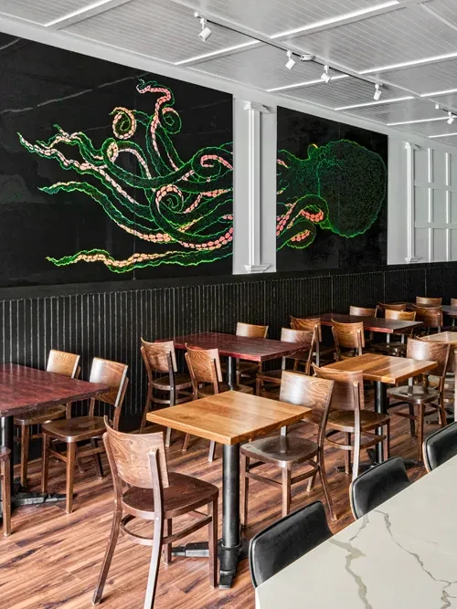 Restaurant dining room with a large, vibrant green octopus mural.