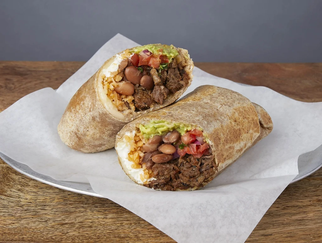 Two burritos, one cut in half, filled with meat, beans, and rice.
