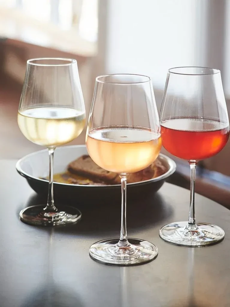 Three wine glasses with white, rosé, and red wine.