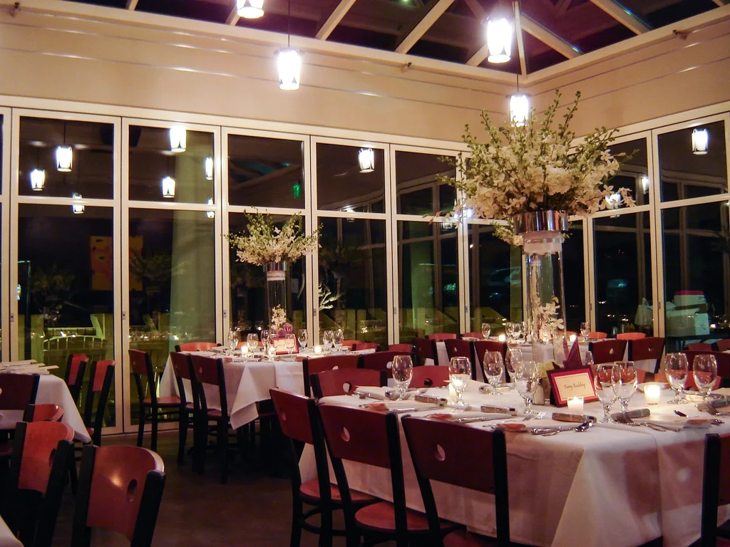 A large dining room with tables set and a large floral centerpiece.