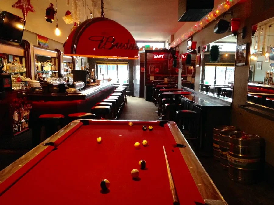 A red-felt pool table in an empty bar with Christmas decorations.