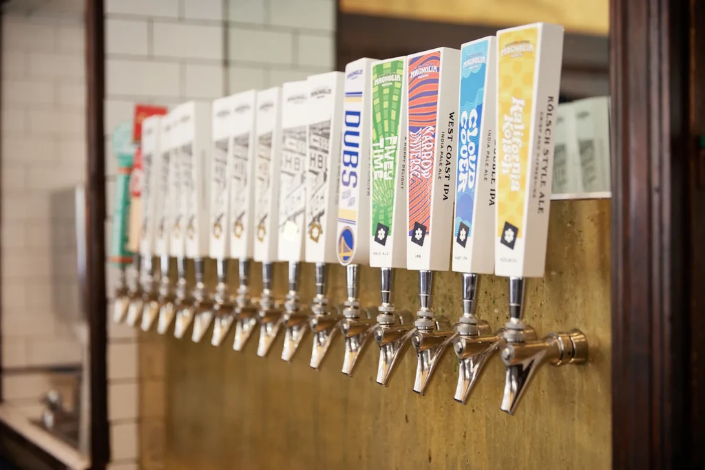 A row of beer taps with branded handles against a golden wall.