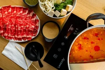 Overhead view of a hot pot with thinly sliced raw beef and vegetables.