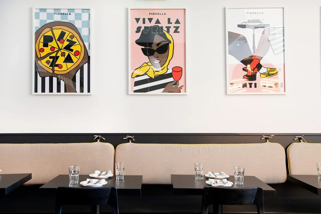 Three framed graphic art prints hang above restaurant booth seating.