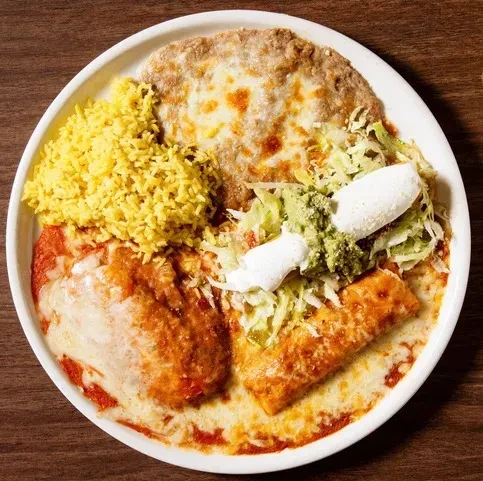 White plate of enchiladas, rice, refried beans, and guacamole.