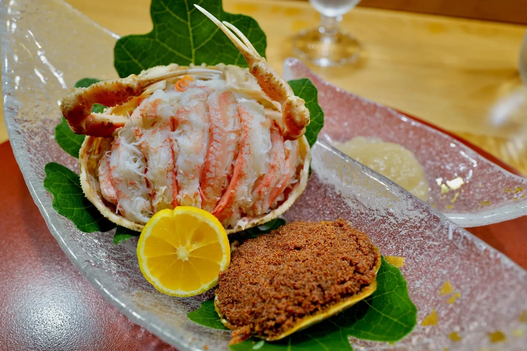 Served crab meat, roe, and lemon on a clear glass platter.