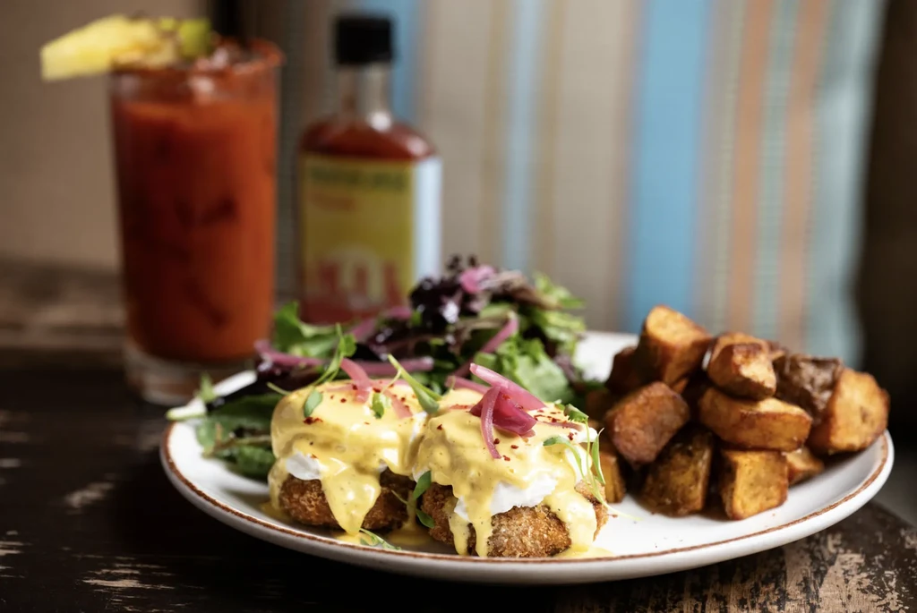 Eggs Benedict with salad, home fries, and a Bloody Mary.