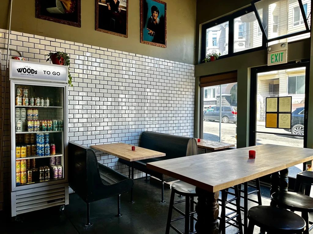 Interior view of a cafe with tables, chairs, and a drink cooler.