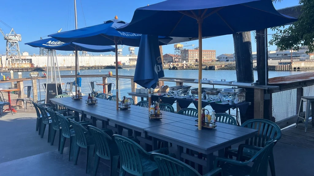 Outdoor dining patio at a restaurant overlooking a working waterfront.