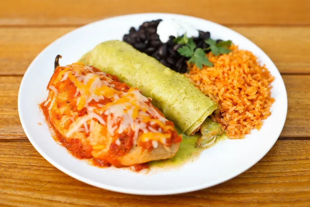 A plate with chile relleno, green enchilada, rice, and black beans.