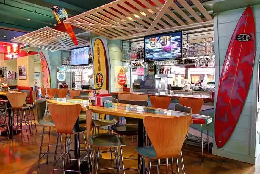 An empty bar and dining area decorated with surfboards.