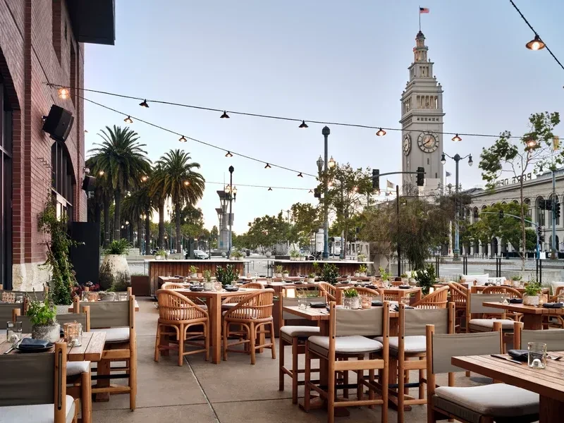 Outdoor restaurant patio with Ferry Building clock tower in background.