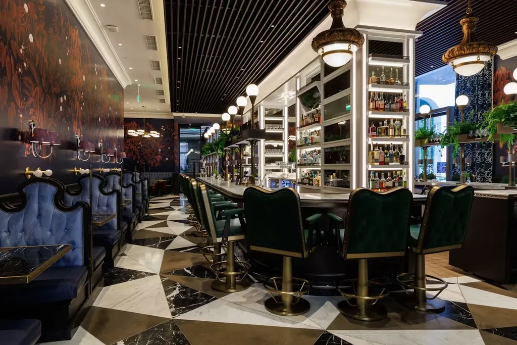 Stylish bar with blue booths, green stools, and black and white floor.