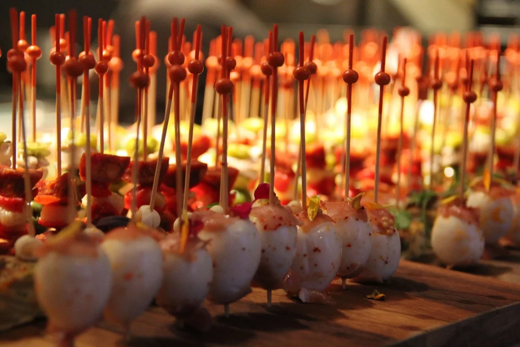 Numerous canapés and small appetizers are arranged on a wooden board.